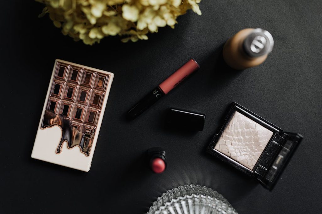eyeliner-lipstick-and-powder-on-black-table-4938514 Flat lay of luxury makeup items on a black table with cosmetics and accessories.